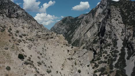 Aerial-shot-curving-around-a-rock-formation-to-reveal-a-road-winding-through-the-Utah-mountain's-valley