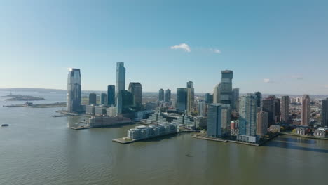 Aerial-panoramic-view-of-tall-apartment-or-office-buildings-on-Hudson-river-waterfront.-Two-long-piers-protruding-into-water.-Jersey-City,-USA