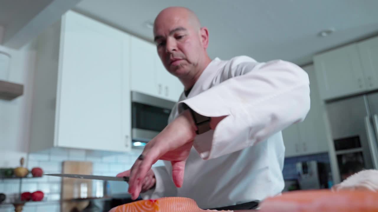 A low-angle shot of a chef cutting slabs of fresh salmon, showcasing their technique and precision in preparing the fish for sushi or other dishes.