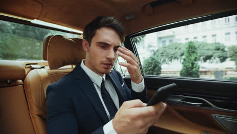 retrato de un hombre de negocios molesto recibiendo malas noticias con un teléfono inteligente en un coche de negocios.