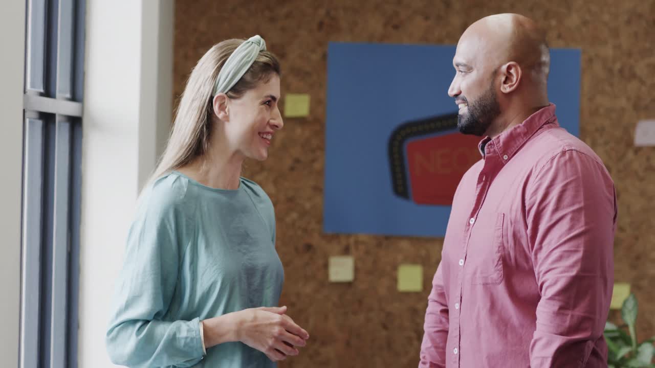 dos diseñadores creativos felices y diversos en discusión en una oficina casual, cámara lenta