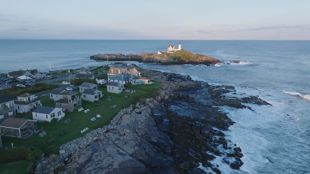 tomada aérea de un dron de york beach, maine, volando hacia el faro de cape neddick nubble al atardecer