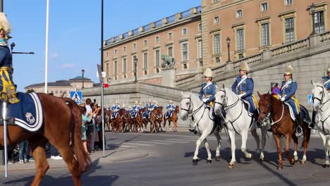 slomo of uniformed royal guards riding horses by stockholm palace on sweden’s national day
