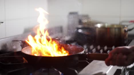 close up view in slow motion of a chef sautéing vegetables in a pan with oil