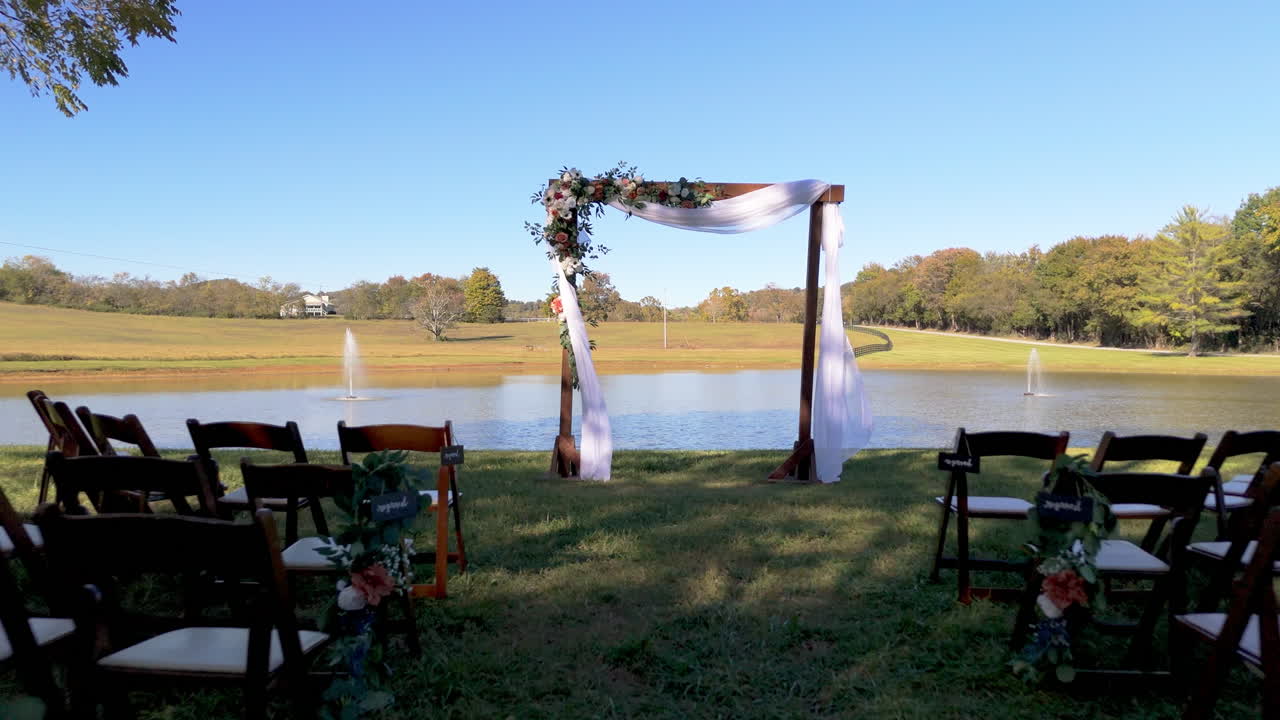 Dolly back from a quiet wedding arch—white drapes, fresh blooms, and open skies set the mood for love, hope, and a moment waiting to begin