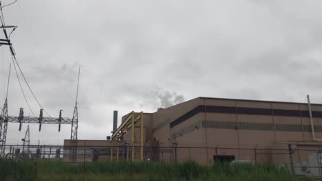 Steam-rising-from-a-steel-plant,-gray-skies,-brick-building,-railroad-tracks