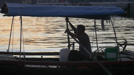 silhoutted man on traditional vietnamese boat