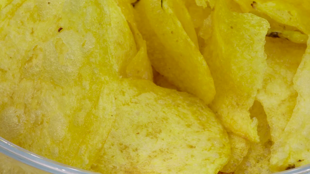Macro shot potato chips pile into transparent glass bowl, Close up view in 4k