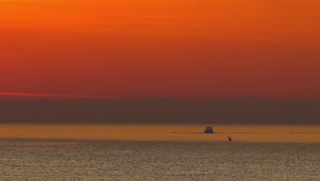 barco de pesca y kayak en mar en calma bajo el cielo naranja del amanecer