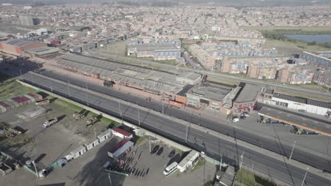 Vista-Aérea-De-Edificios-Cerca-De-Una-Carretera-Con-Autos-Moviéndose-En-Una-Mañana-Soleada