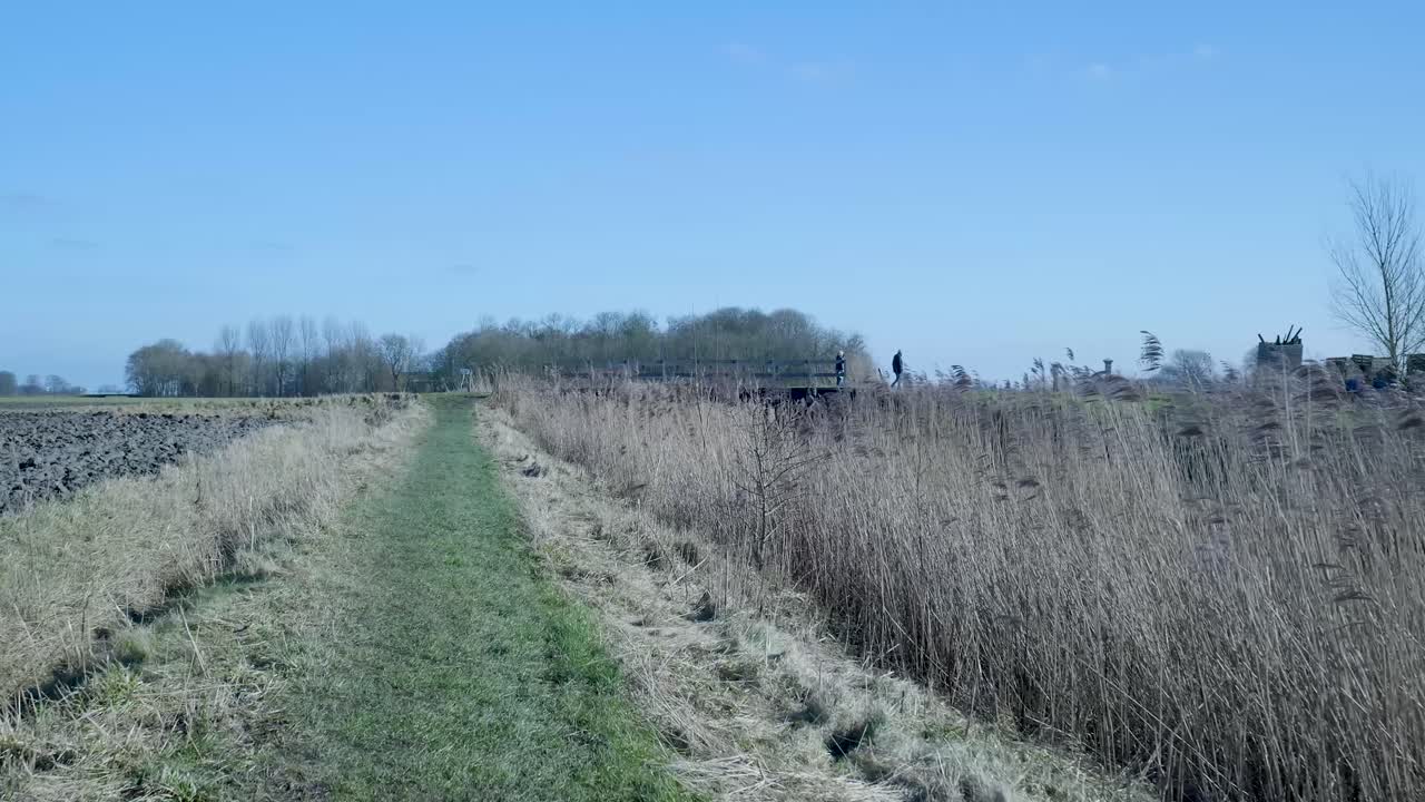 Two People Walking on a Distant Bridge in a Rural Landscape