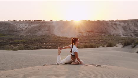 joven instructora de yoga morena actuando en la arena durante el amanecer