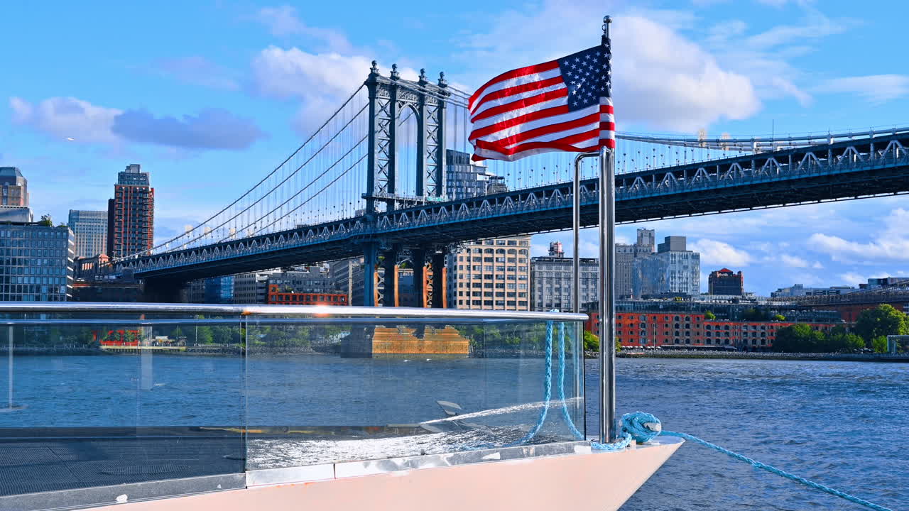Front part of the boat with a set American flag waving gin the wind. Low angle view at the Manhattan Bridge in New York, USA