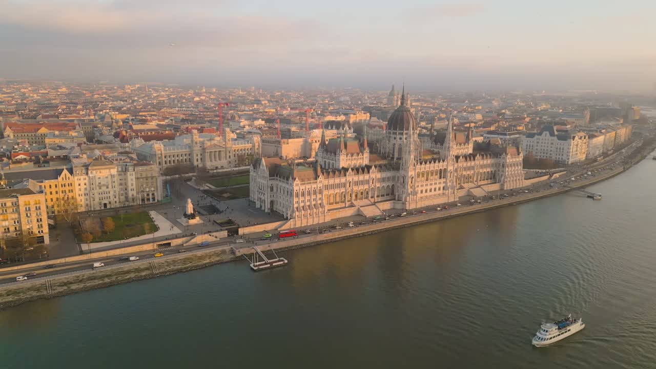 Breathtaking drone footage of the majestic Hungarian Parliament Building and the Danube River at sunset. The building grids of the dreamy city can be seen in the frame's backdrop