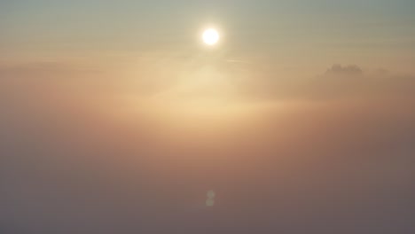 황금색 겨울 안개 위에서 왼쪽에서 오른쪽으로 파닝하는 해가 뜨는 드론 뷰