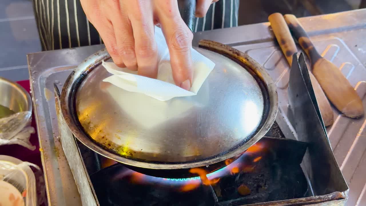 A street food vendor cooks fried eggs in a pan over a blue gas flame