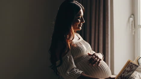 pregnant woman reading by the window