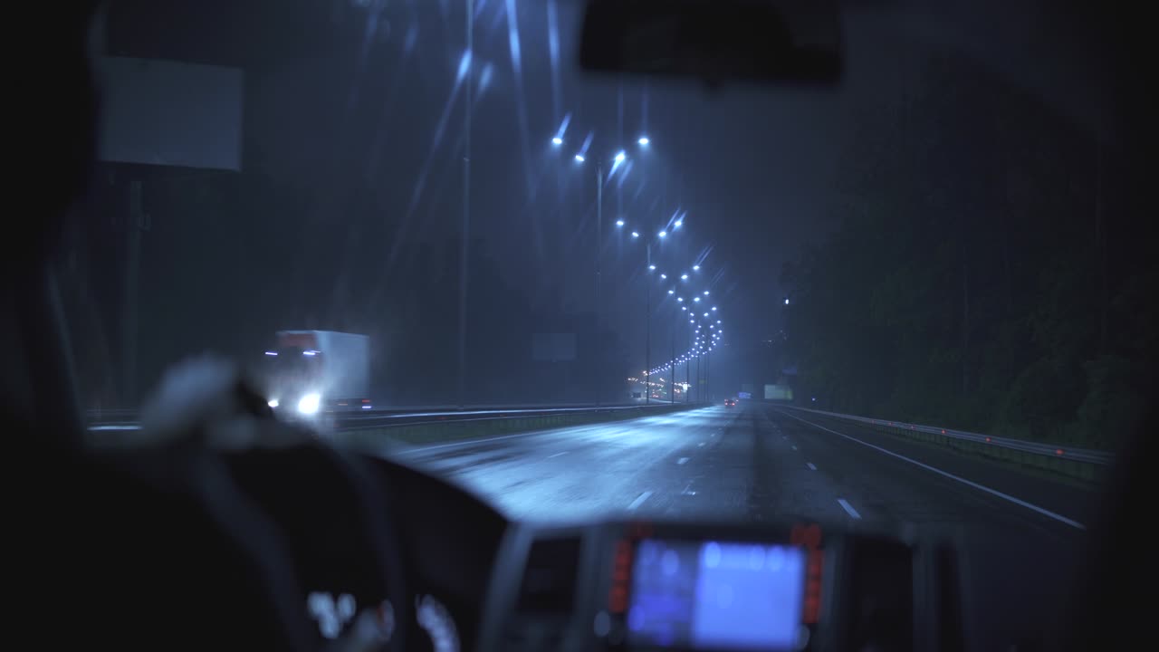 el hombre conduciendo en un camino de noche mojado