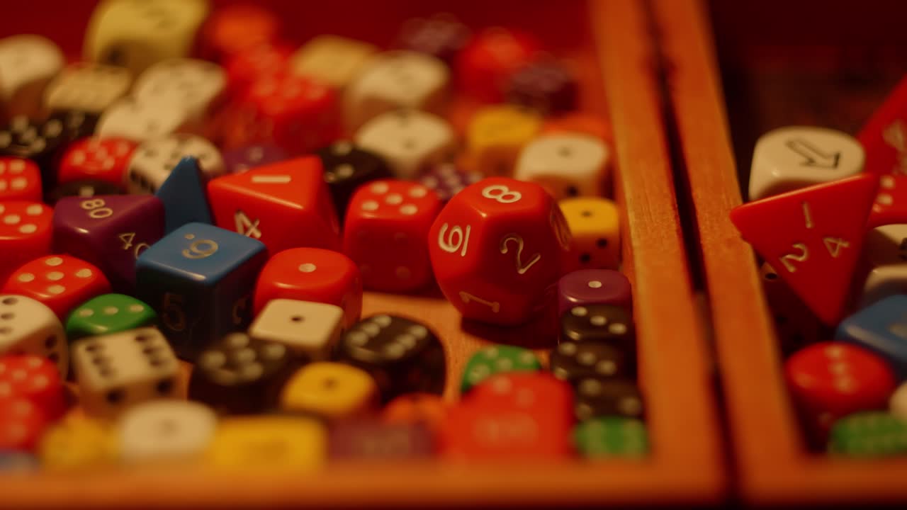 Variety of colorful dices laying inside of wooden box, slider shot, left to right