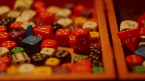 variety of colorful dices laying inside of wooden box, slider shot, left to right