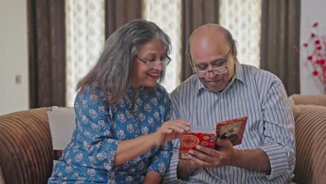 Happy-Old-Indian-couple-laughing-and-going-through-photo-album