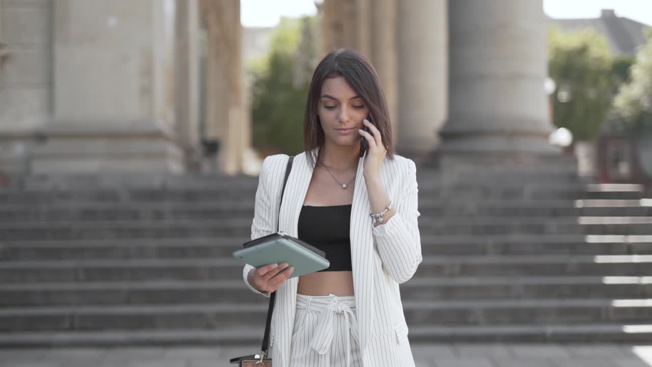 en smuk pige, der taler i telefonen, mens hun går ned ad trappen.