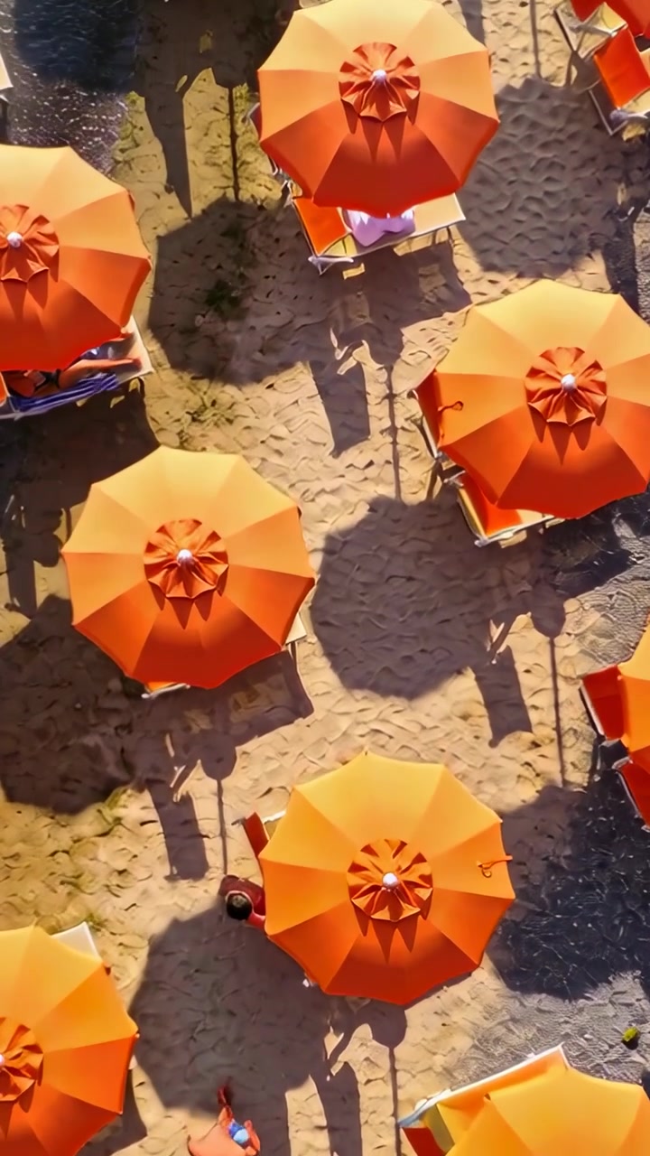 Video verticale: Drone in volo che mostra ombrelloni arancioni sulla spiaggia con un uomo in costume da bagno che tiene un oggetto