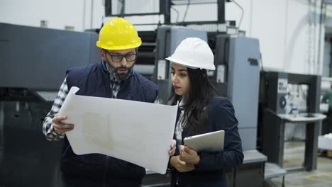 front view of printing employees inspecting plan of building