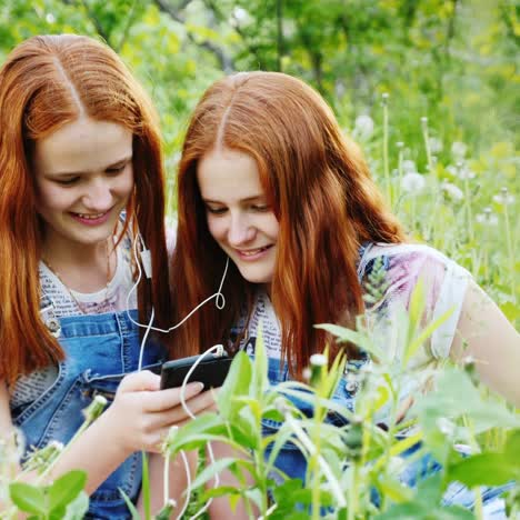 two cool twins girls are listening to music outdoors