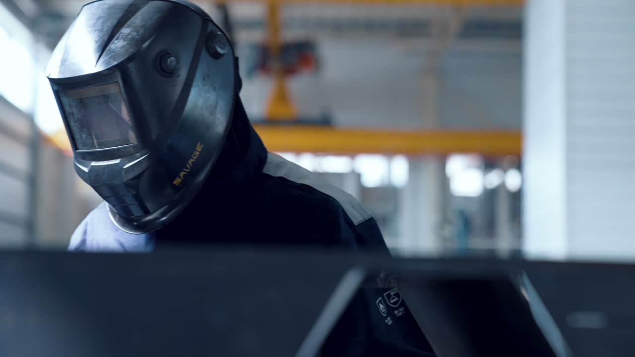 VINNYTSIA, UKRAINA - 19 JANUARI 2023: Man med hjälm svetsar metall med gnistor som sprutar ut.