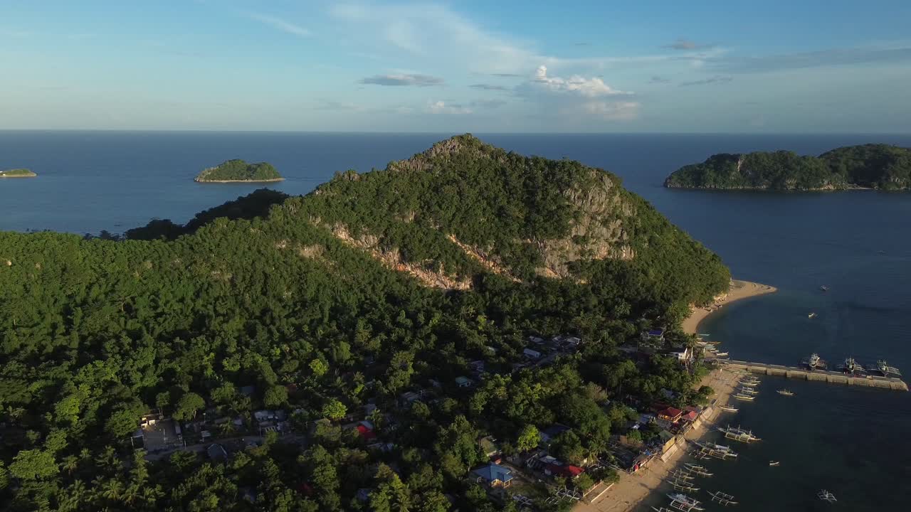Filipinler Guimaras Adası'nda, kıyı boyunca demirlemiş teknelerle küçük bir iskele limanının havadan drone görüntüsü. Sakin mavi denizle çevrili, kıyı köylerini birbirine bağlayan tropikal bir ada ulaşım merkezi.