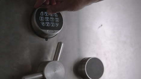 A man's hand punches in a combination on a keypad and then proceeds to open a safe door