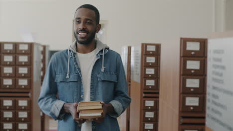 man holding books in a library