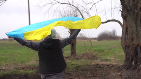 woman flag of ukraine near burnt tree