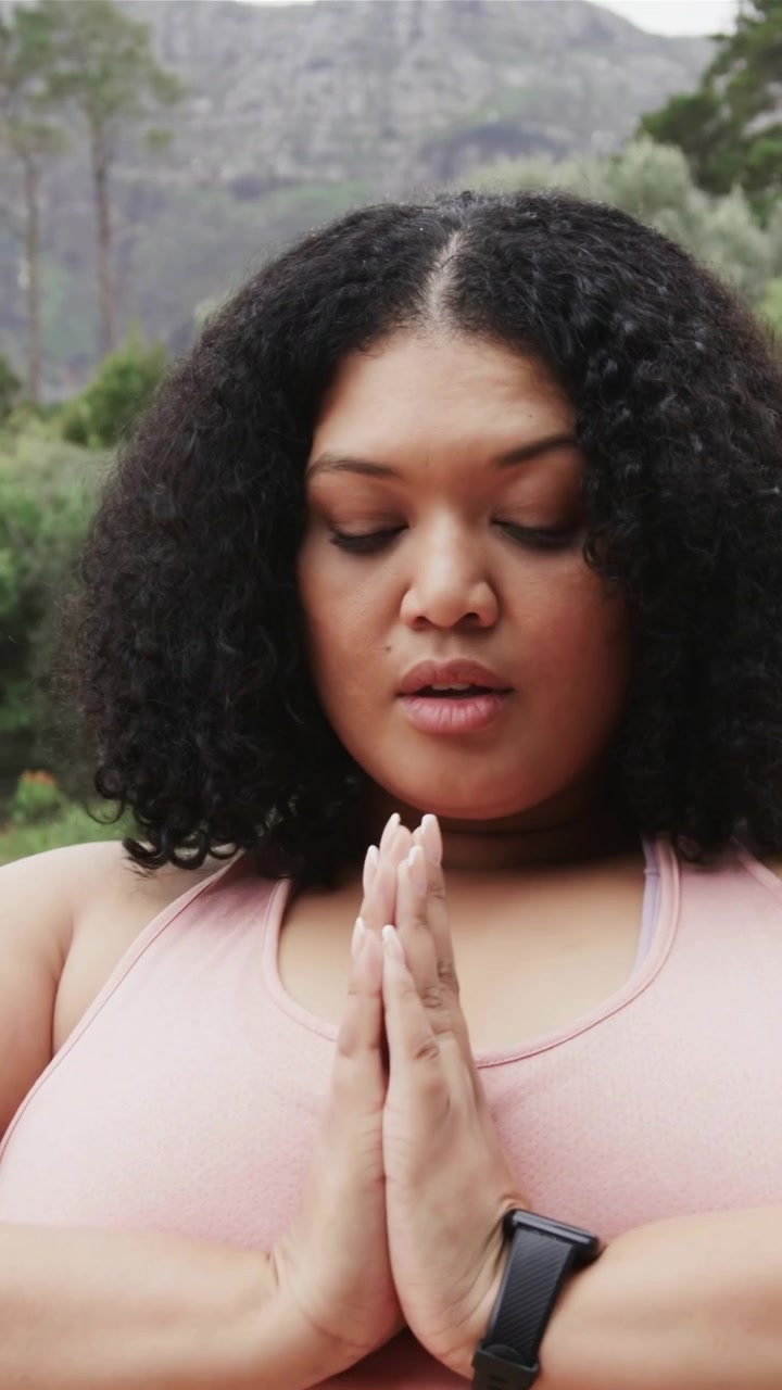 Vertical video: Raising arm, woman in pink top lifting arms, praying and centering on balcony