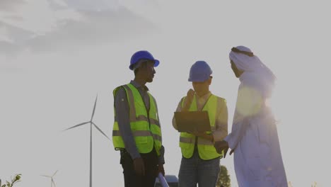 blue collar workers electrical engineer team and architect holding consulting plan for construction of windmill field in mountains. landscape architecture use wind turbine to produce pure energy.