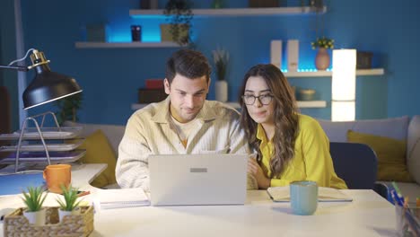 marido y mujer emocionados mirando la computadora portátil con la esperanza de buenas noticias.