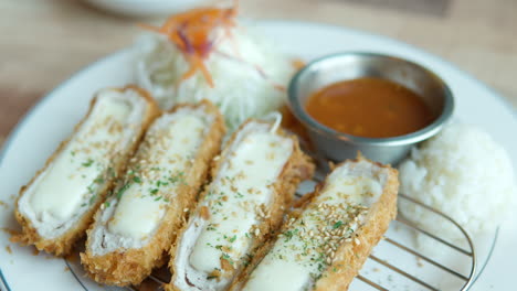 일본 치즈 톤카쓰 (tonkatsu) 가 소스와 고추  ⁇ 러드와 세자임 토핑으로 접시에 클로즈업으로 드러납니다.