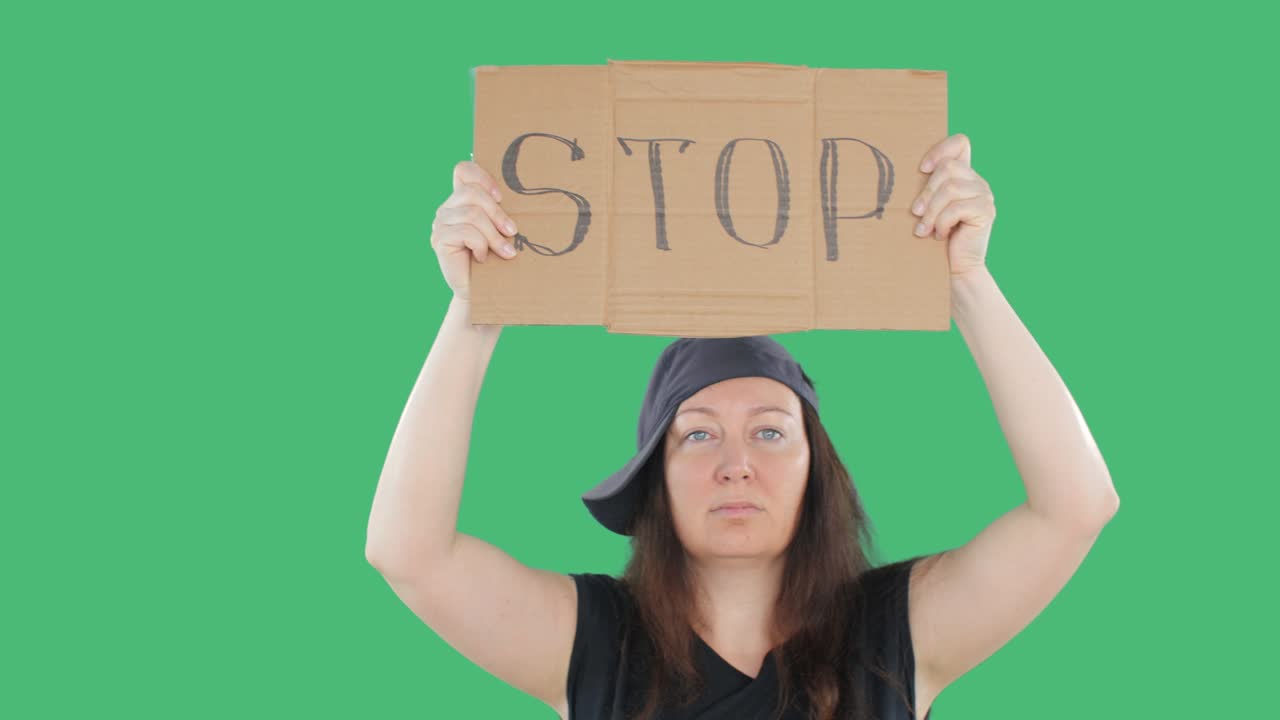 Adult woman in cap showing cardboard with stop sign on manifestation. Green background. People rebellion and national revolution. Civil unrest concept