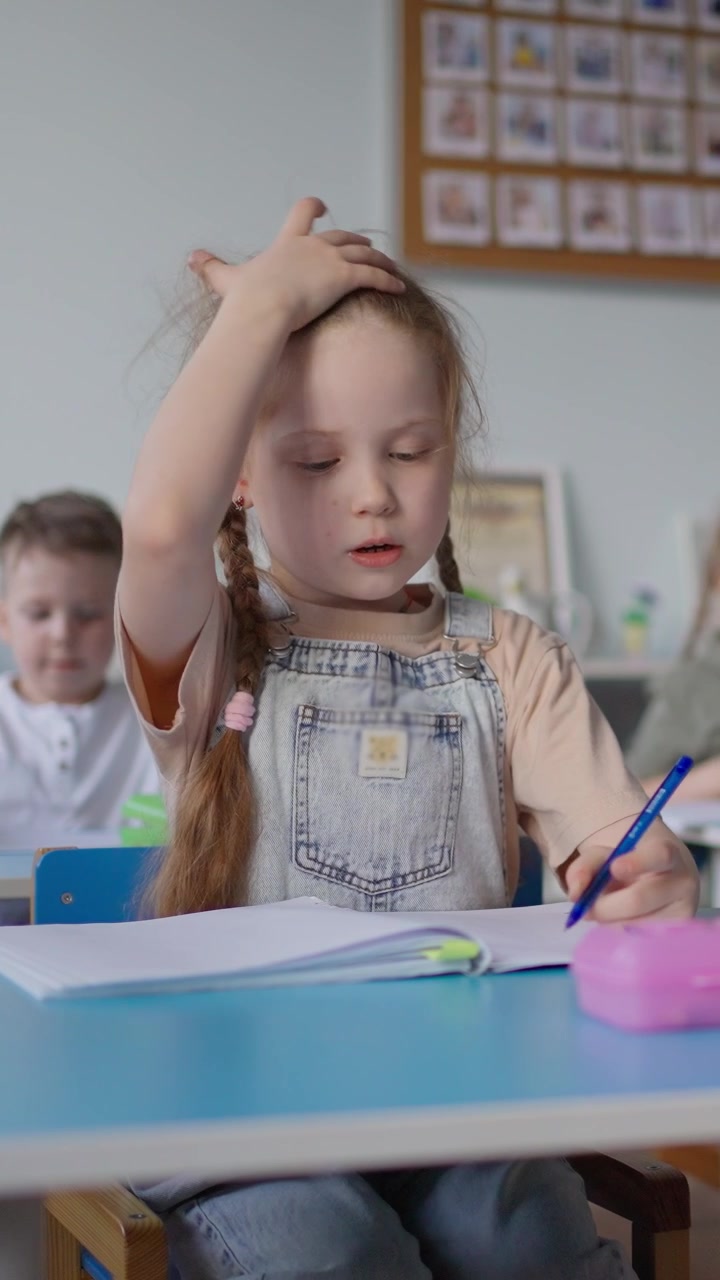 Bambina concentrata che scrive sul suo quaderno a scuola