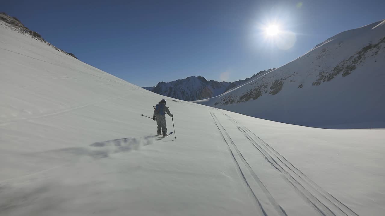 paseo libre fuera de pista esquiador esquiando en nieve fresca de polvo profundo esquiando hacia el sol con un increíble cielo azul y vistas a las montañas