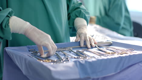 midsection of female surgeon preparing surgical instruments in theatre, copy space, slow motion