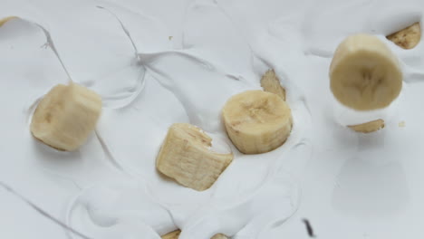 sweet banana falling yogurt making splashes in super slow motion close up.
