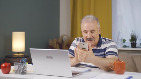 Home-office-worker-old-man-talking-on-the-phone-facetime-happily.