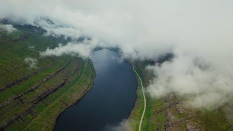 Aerial View of a Fjord and Lush Green Mountains Partially Covered by Clouds