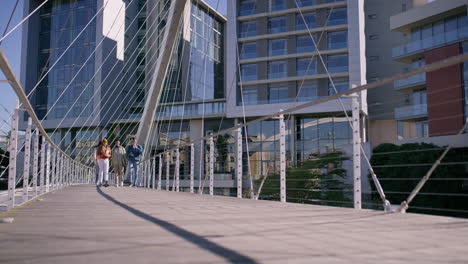 people walking on a modern bridge in a city