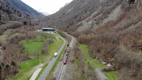 aerial: passenger train in a valley by a road with light traffic in the pyrenees, southern france