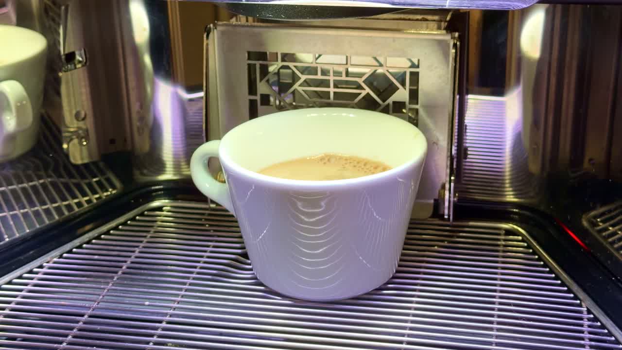Freshly brewed hot chocolate pouring into white cup from modern coffee machine