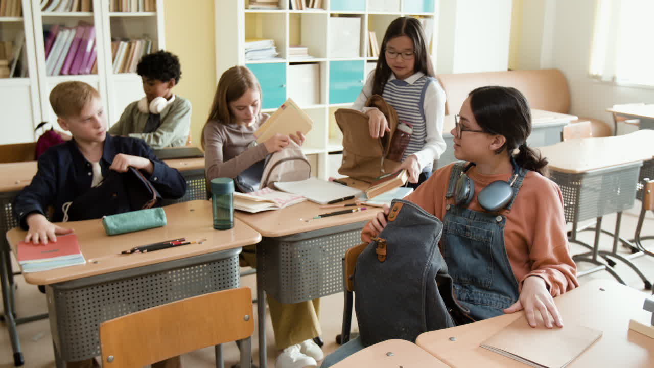 Students in a classroom putting books and items into their backpacks