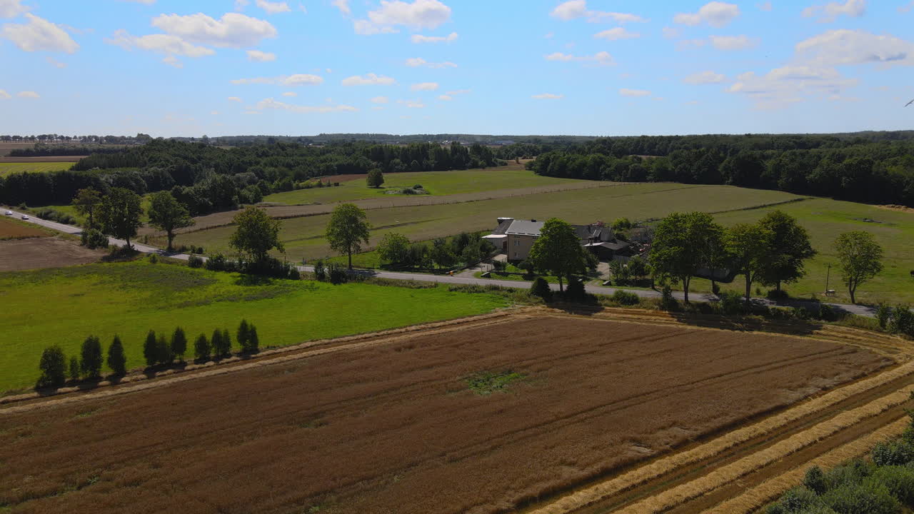 Scenic Landscape Of A Modern House In The Middle Of Farmland, Lush Greenery And Blue Sky At The Background In Puck, Poland. - Aerial Shot